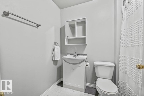The bathroom features a white vanity with cabinet storage, a wall-mounted medicine cabinet, and a toilet - 8737 83 Avenue, Edmonton, AB - Indoor Photo Showing Bathroom