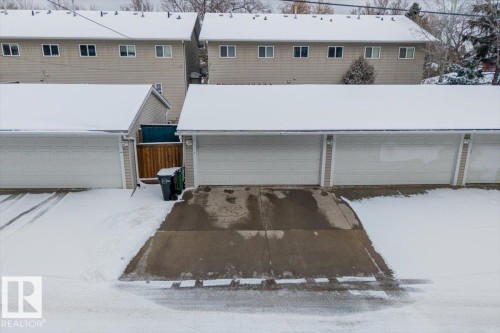 Multi-stall garage structure with individual bay doors, concrete driveways, and a wooden privacy fence - 8737 83 Avenue, Edmonton, AB - Outdoor