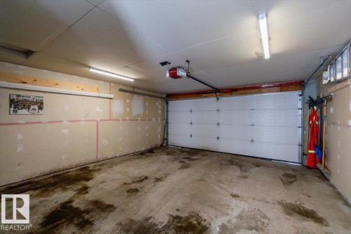 Spacious garage with a concrete floor, overhead lighting, and an automatic garage door opener - 8737 83 Avenue, Edmonton, AB - Indoor Photo Showing Garage