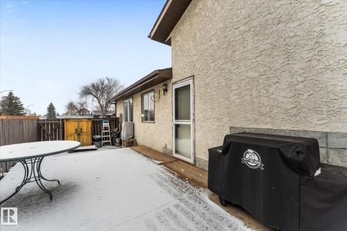 The property features an exterior entrance to a patio area with a wooden fence - 3908 44 Avenue, Stony Plain, AB - Outdoor