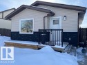 The property features light-colored horizontal siding, a dark-colored textured foundation, and a contrasting brown roofline with matching gutters - 3908 44 Avenue, Stony Plain, AB  - Outdoor With Deck Patio Veranda With Exterior 