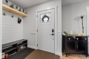 The inviting entryway features a white paneled wall with a natural wood shelf, a dark wood bench with shoe storage, and a white entry door with decorative glass - 3908 44 Avenue, Stony Plain, AB  - Indoor Photo Showing Other Room 