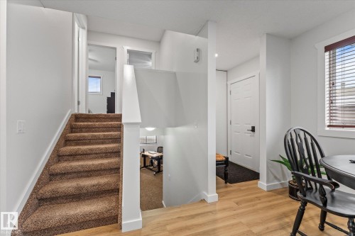 Interior hallway featuring light wood flooring, a carpeted staircase, and a doorway leading to a separate room - 3908 44 Avenue, Stony Plain, AB - Indoor Photo Showing Other Room
