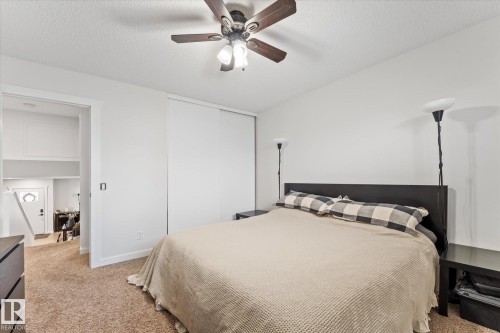 The property features a bedroom with a ceiling fan, carpeted flooring, and a large sliding door closet - 3908 44 Avenue, Stony Plain, AB - Indoor Photo Showing Bedroom