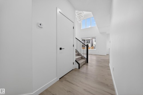 Entryway featuring light wood-finish flooring, white walls, and a modern staircase with black metal railings and carpeted treads - 3906 41 Avenue, Beaumont, AB - Indoor Photo Showing Other Room