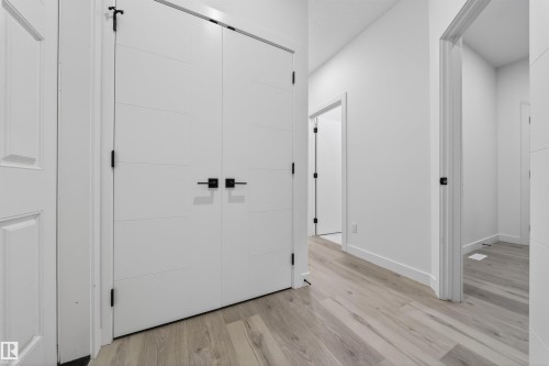 Hallway featuring light wood-finish flooring, white walls, and contemporary doors with matte black hardware - 3906 41 Avenue, Beaumont, AB - Indoor Photo Showing Other Room