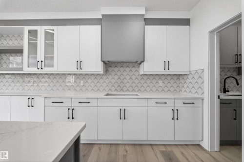 Modern kitchen featuring white cabinetry, quartz countertops, a patterned tile backsplash, and wood-finish flooring - 3906 41 Avenue, Beaumont, AB - Indoor