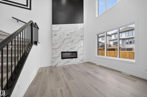 Living area featuring a modern electric fireplace with a marble-finish surround and a black vertical slat accent wall - 3906 41 Avenue, Beaumont, AB - Indoor With Fireplace