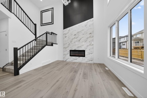 Contemporary living area featuring a striking fireplace wall with a linear electric fireplace, marble-look surround, and black vertical paneling - 3906 41 Avenue, Beaumont, AB - Indoor With Fireplace
