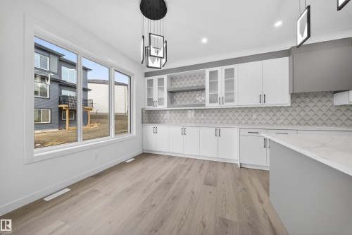 Contemporary kitchen featuring white cabinetry, a patterned backsplash, and an island with a light-colored countertop - 3906 41 Avenue, Beaumont, AB - Indoor Photo Showing Kitchen With Upgraded Kitchen
