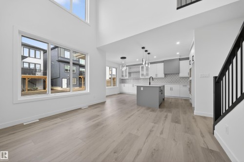 Open-concept living area featuring wood-finish flooring, a two-story ceiling, and large windows - 3906 41 Avenue, Beaumont, AB - Indoor Photo Showing Kitchen