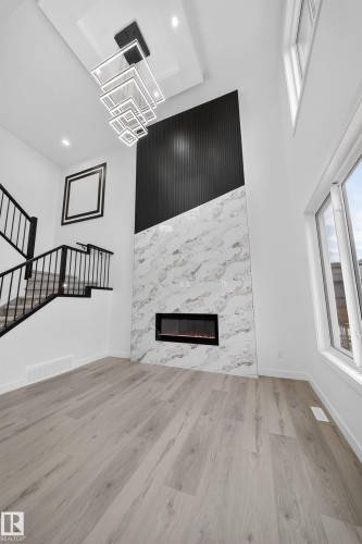 Two-story living area featuring a prominent fireplace wall with a linear electric fireplace, marble-look paneling, and black fluted paneling - 3906 41 Avenue, Beaumont, AB - Indoor With Fireplace