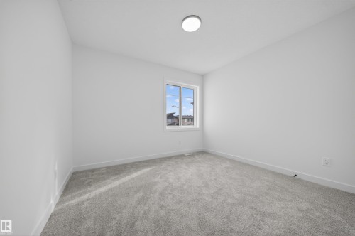 Bright interior featuring light grey carpeting, white painted walls, and a single window with white trim - 3906 41 Avenue, Beaumont, AB - Indoor Photo Showing Other Room