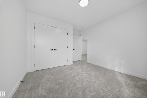 Spacious room featuring light gray carpeting, white walls, white trim, a flush mount ceiling light, and a white double door closet with black hardware - 3906 41 Avenue, Beaumont, AB - Indoor Photo Showing Other Room