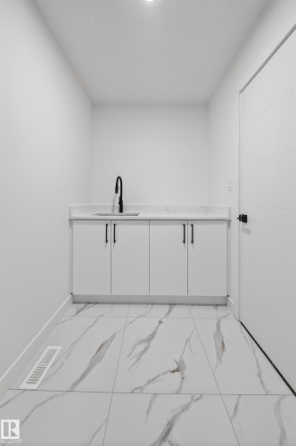 Utility area featuring a white shaker-style vanity with a quartz-finish countertop and a black gooseneck faucet - 3906 41 Avenue, Beaumont, AB - Indoor Photo Showing Other Room