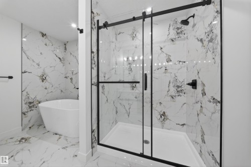 Spacious bathroom featuring a frameless glass shower enclosure with matte black hardware, a rainfall showerhead, and a freestanding soaking tub - 3906 41 Avenue, Beaumont, AB - Indoor Photo Showing Bathroom