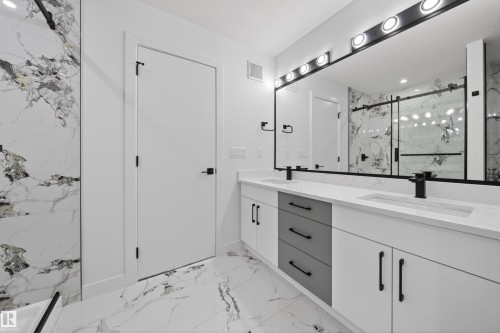 Dual vanity with integrated sinks and matte black fixtures, set against a full-width mirror with overhead lighting - 3906 41 Avenue, Beaumont, AB - Indoor Photo Showing Bathroom