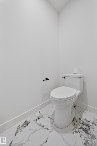 White two-piece toilet featuring a black toilet paper holder - 3906 41 Avenue, Beaumont, AB - Indoor Photo Showing Bathroom