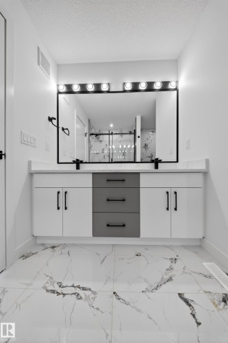 Contemporary bathroom vanity featuring dual sinks, a large mirror with integrated lighting, and a white countertop - 3906 41 Avenue, Beaumont, AB -  Photo Showing Other Room