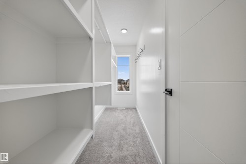 Walk-in closet featuring extensive built-in shelving, gray carpet flooring, a natural light window, and recessed ceiling lighting - 3906 41 Avenue, Beaumont, AB - Indoor Photo Showing Other Room