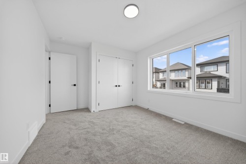 Expansive window offering exterior views, light gray carpet, white walls, two interior doors with black hardware, and a ceiling-mounted light fixture - 3906 41 Avenue, Beaumont, AB - Indoor Photo Showing Other Room