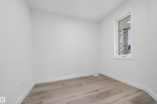 Neutral interior space featuring light wood-finish flooring, white baseboards, and a single window with white trim - 3906 41 Avenue, Beaumont, AB - Indoor Photo Showing Other Room