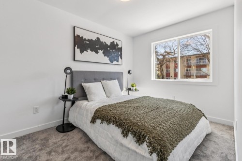 Bright room featuring a large window, plush gray carpeting, white walls, and a gray upholstered headboard - 10726 107 Street, Edmonton, AB - Indoor Photo Showing Bedroom