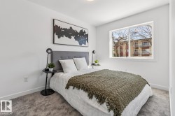 Bright room featuring a large window, plush gray carpeting, white walls, and a gray upholstered headboard - 