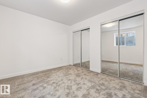 Carpeted room with a ceiling-mounted light fixture, white baseboards, and two mirrored sliding closet doors - 10726 107 Street, Edmonton, AB - Indoor Photo Showing Other Room