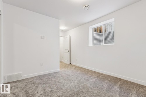 Carpeted room featuring white walls, a single window with horizontal blinds, and a white baseboard trim - 10726 107 Street, Edmonton, AB - Indoor Photo Showing Other Room