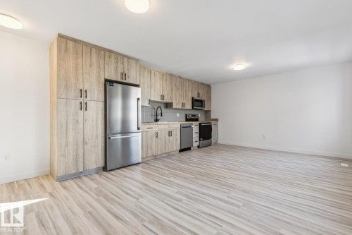 Kitchenette featuring wood-finish cabinetry, stainless steel appliances, a subway tile backsplash, and light wood-finish flooring - 10726 107 Street, Edmonton, AB - Indoor Photo Showing Kitchen With Stainless Steel Kitchen