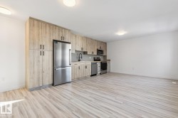 Kitchenette featuring wood-finish cabinetry, stainless steel appliances, a subway tile backsplash, and light wood-finish flooring - 