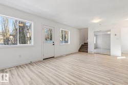 Bright living space featuring light wood-finish flooring, white walls, and multiple windows - 