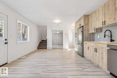 Open-concept kitchen and living area featuring wood-finish flooring, light wood-look cabinetry, stainless steel appliances, and a subway tile backsplash - 10726 107 Street, Edmonton, AB - Indoor Photo Showing Kitchen