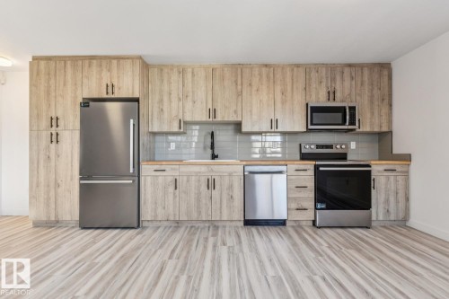 Contemporary kitchen featuring wood-finish cabinetry, stainless steel appliances, and wood-finish countertops - 10726 107 Street, Edmonton, AB - Indoor Photo Showing Kitchen With Stainless Steel Kitchen