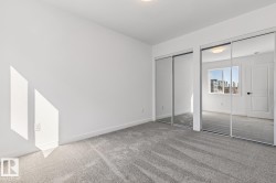 Room featuring light gray carpeting, crisp white walls, and dual mirrored closet doors - 