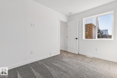 Bright room featuring light gray carpeting, white walls, and a white interior door with black hardware - 10726 107 Street, Edmonton, AB - Indoor Photo Showing Other Room