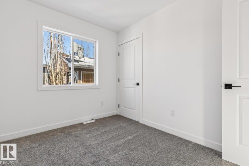 Bright room with a large window, soft gray carpet, two white paneled doors, and contemporary black hardware - 10726 107 Street, Edmonton, AB - Indoor Photo Showing Other Room