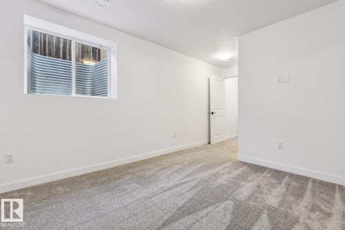 Spacious room featuring a white-framed window with a metal window well - 10726 107 Street, Edmonton, AB - Indoor Photo Showing Other Room