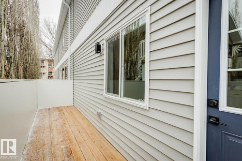 Private outdoor deck area featuring wood flooring, a white privacy wall, and grey horizontal siding - 10726 107 Street, Edmonton, AB - Outdoor With Deck Patio Veranda With Exterior