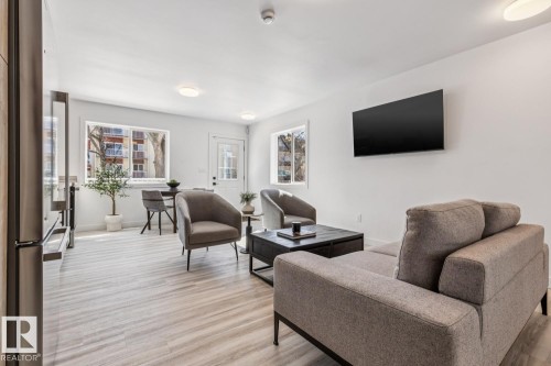 Bright living area featuring wood-finish flooring and ample natural light from multiple windows - 10726 107 Street, Edmonton, AB - Indoor Photo Showing Living Room
