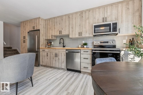 Contemporary kitchen featuring wood-finish cabinetry and light wood-finish flooring - 10726 107 Street, Edmonton, AB - Indoor Photo Showing Kitchen With Stainless Steel Kitchen