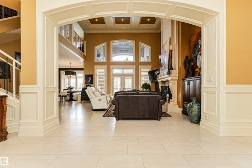 An impressive entryway with a grand archway, decorative wainscoting, and light-colored tile flooring - 3048 Watson Landing, Edmonton, AB - Indoor With Fireplace