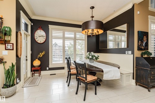 This dining area features light-colored tile flooring, a built-in bench seating area, and a drum-style chandelier - 3048 Watson Landing, Edmonton, AB - Indoor Photo Showing Dining Room