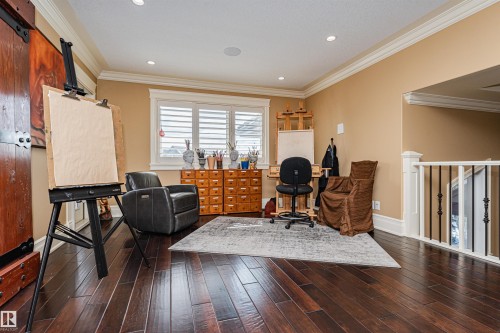 This versatile space features dark hardwood flooring, crown molding, recessed lighting, and a window with white shutters - 3048 Watson Landing, Edmonton, AB - Indoor
