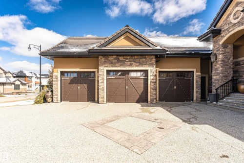 The property features a triple garage with custom doors and a stone and stucco exterior - 3048 Watson Landing, Edmonton, AB - Outdoor