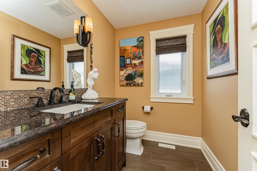 This bathroom features a vanity with a dark wood cabinet, a granite countertop, and a rectangular sink with a dark bronze faucet. It is located on the loft level above the main floor. - 3048 Watson Landing, Edmonton, AB - Indoor Photo Showing Bathroom