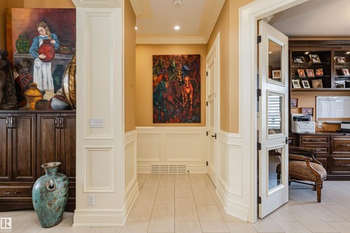This hallway features tile flooring, extensive wainscoting, and a doorway leading to a room with built-in cabinetry - 3048 Watson Landing, Edmonton, AB - Indoor Photo Showing Other Room