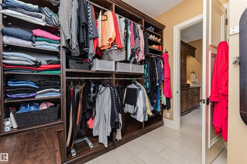 Custom closet system with dark wood cabinetry and ample shelving, offering extensive storage and organization options - 3048 Watson Landing, Edmonton, AB - Indoor With Storage