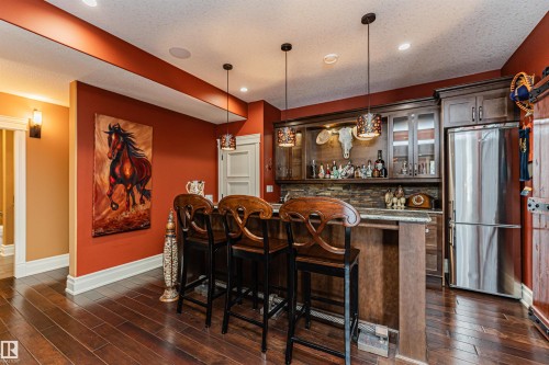 This property features rich hardwood flooring, a fully equipped wet bar with cabinetry, a built-in refrigerator, and recessed lighting - 3048 Watson Landing, Edmonton, AB - Indoor Photo Showing Dining Room